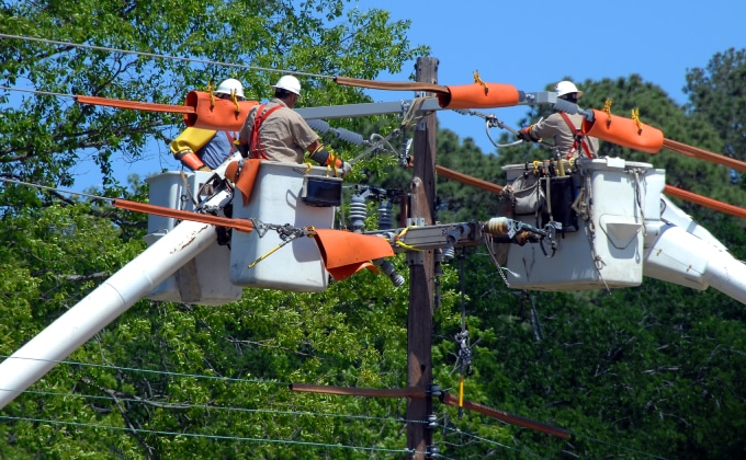 Engineers in bucket trucks working on a transmission line.